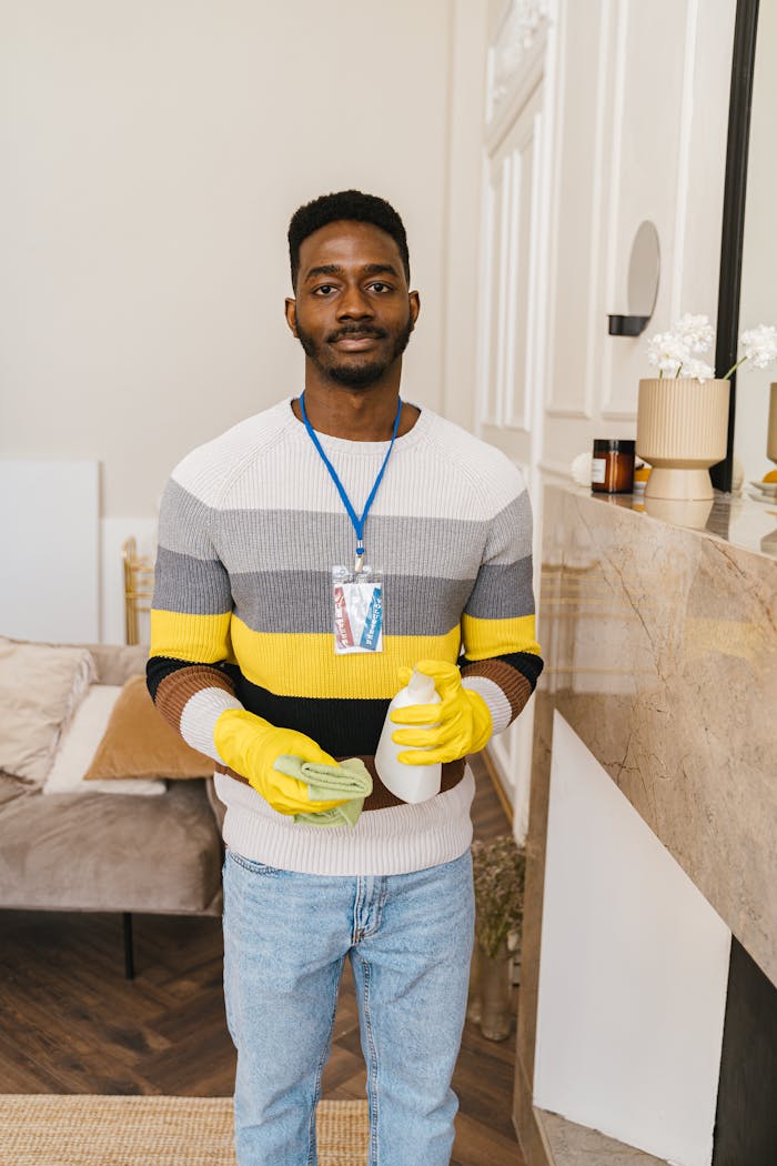 services-03 Young man volunteering, holding cleaning supplies in a modern indoor space.