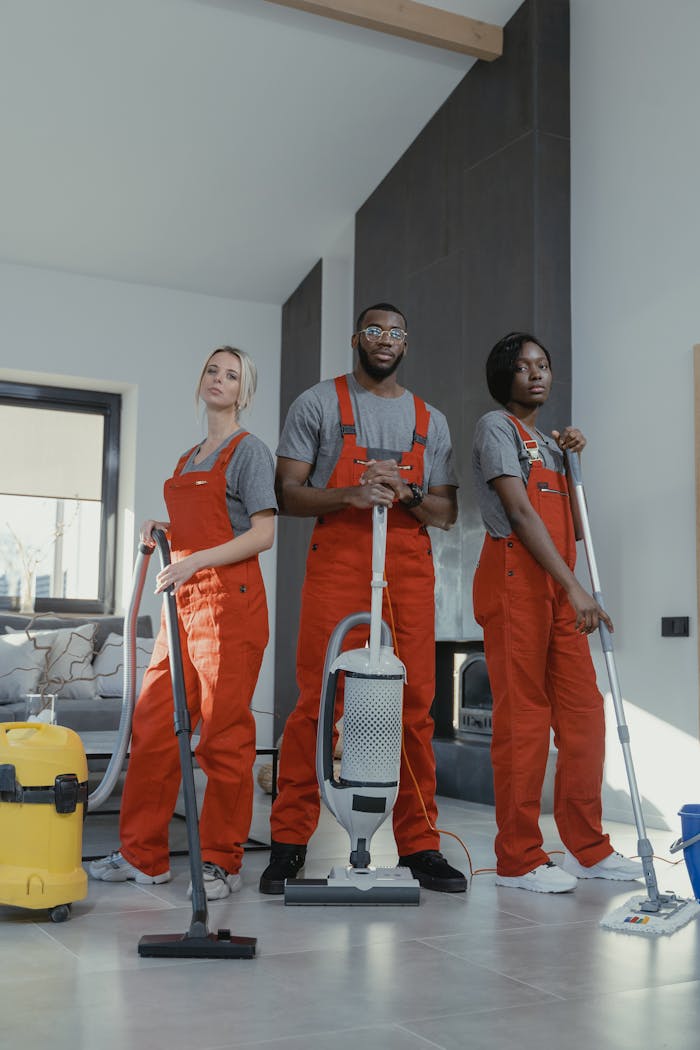 services-02 Three cleaners in uniform with equipment in a modern home interior, showcasing teamwork and professionalism.
